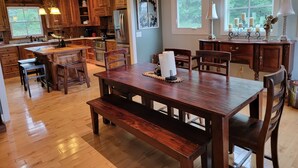 Una cocina amplia con armarios de madera, una isla central y un comedor con mesa y bancos de madera.