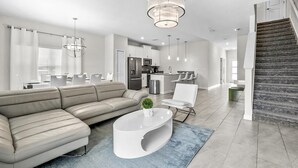 Ein modernes Wohnzimmer mit einem Ecksofa, einem weißen Couchtisch und einer Deckenleuchte.