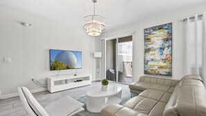 Ein modernes Wohnzimmer mit einer Couch, einem Couchtisch, einem Fernseher und Kunstwerken an den Wänden.