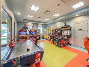 Une pièce avec une table de billard, des jeux d’arcade et une porte.