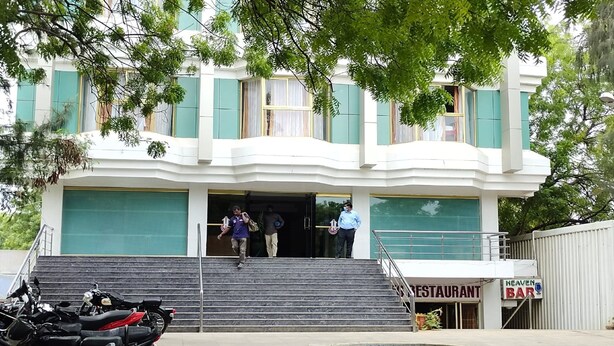 A building with a restaurant and bar sign, a staircase leading to the entrance, and parked motorcycles. - Hotel Geetha International (Thoothukudi)