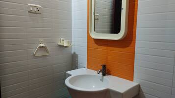 Un baño con lavamanos blanco, espejo y retrete.