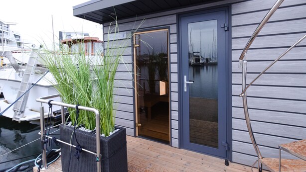 Ein modernes Gebäude mit einer Holterrasse, einer Glastür und einem Metallgeländer.