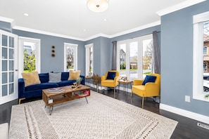 A spacious living room with a blue sofa, yellow armchairs, and a coffee table.
