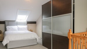 A bedroom with a bed, a nightstand, a wardrobe, a wooden staircase, and a skylight. - 7a Belvoir Terrace (Scarborough)