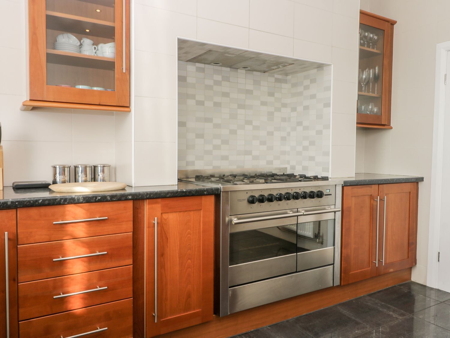 A kitchen with wooden cabinets, a stainless steel stove, and a tiled backsplash.