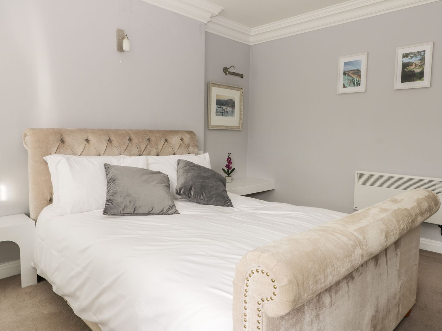A bedroom with a large bed, a headboard, a bedside table, and a radiator.