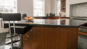 A modern kitchen with a large island, wooden cabinets, and a stainless steel stove. - 7a Belvoir Terrace (Scarborough)
