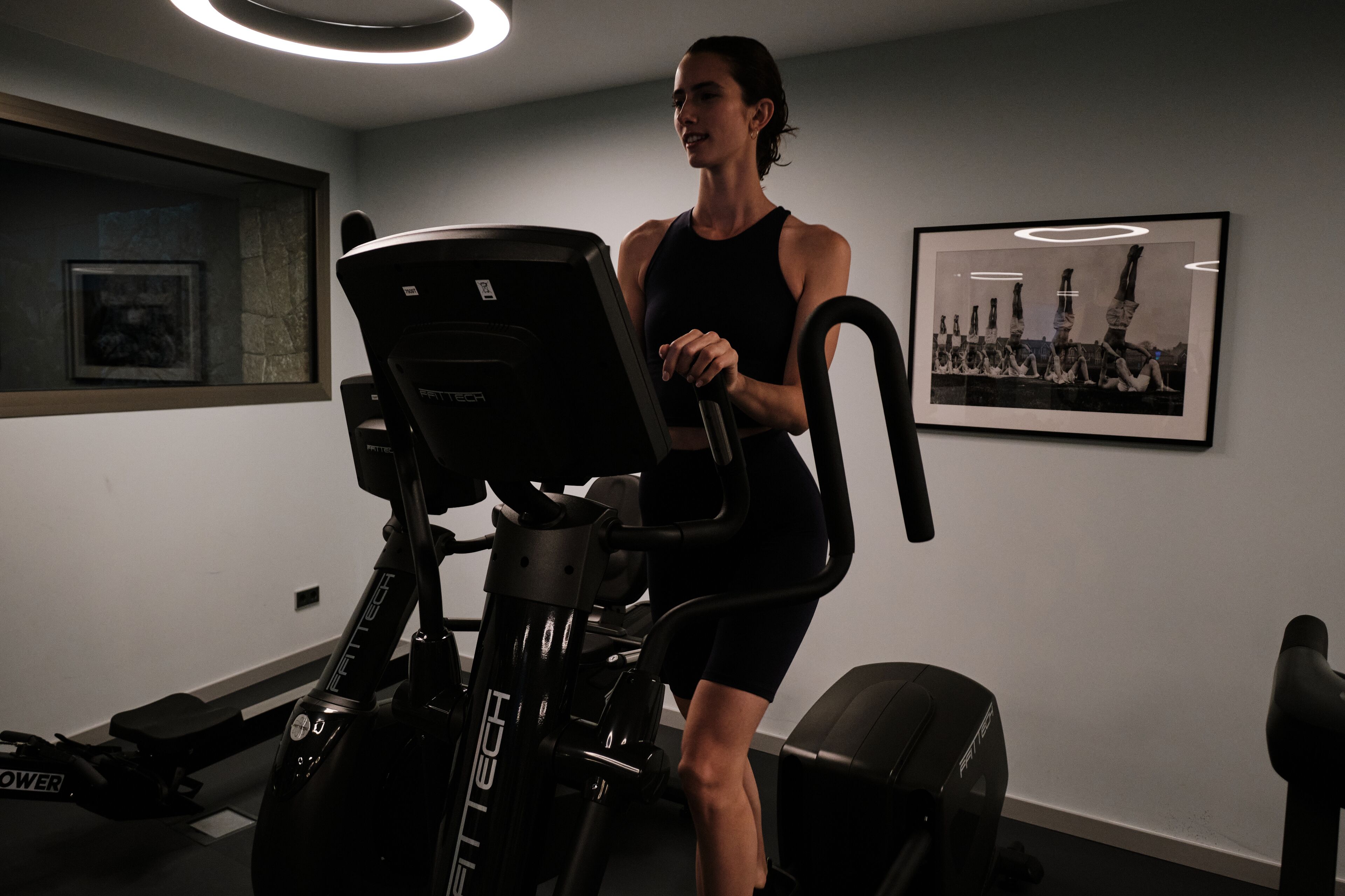 Un gimnasio con una bicicleta estática, un cuadro en la pared y una ventana con vistas.