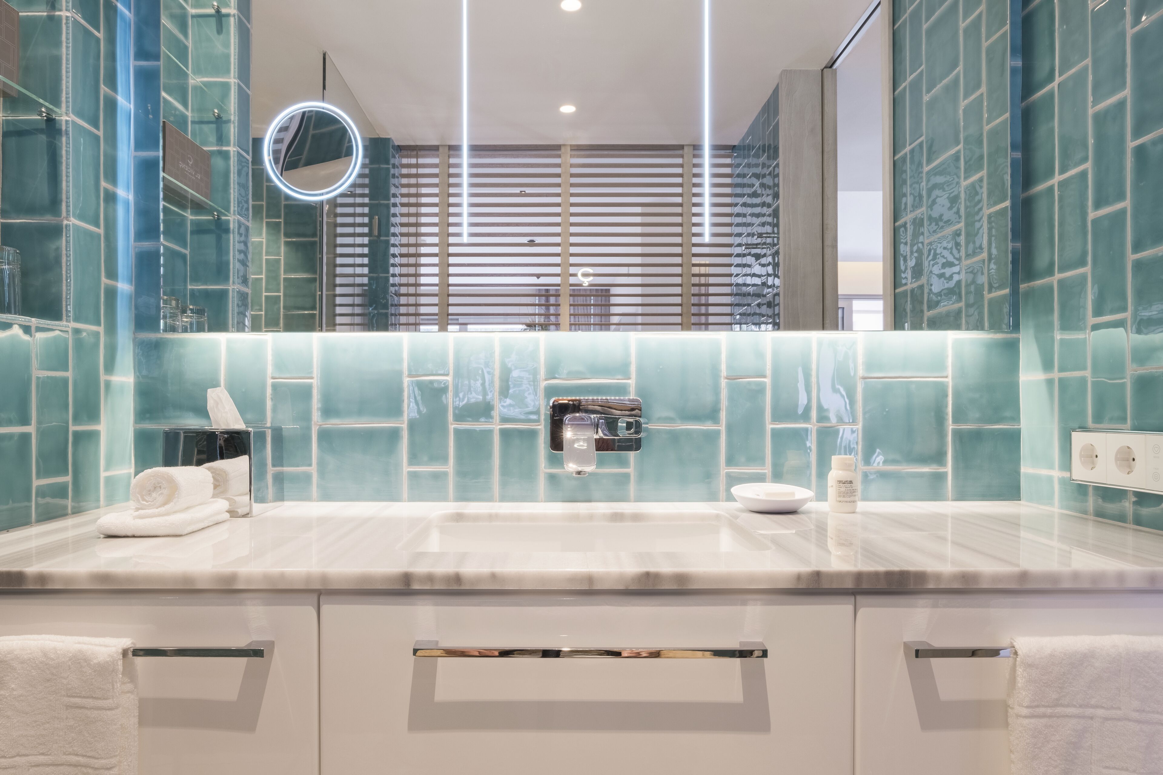 A modern bathroom with a large mirror, a towel rack, and a sink.