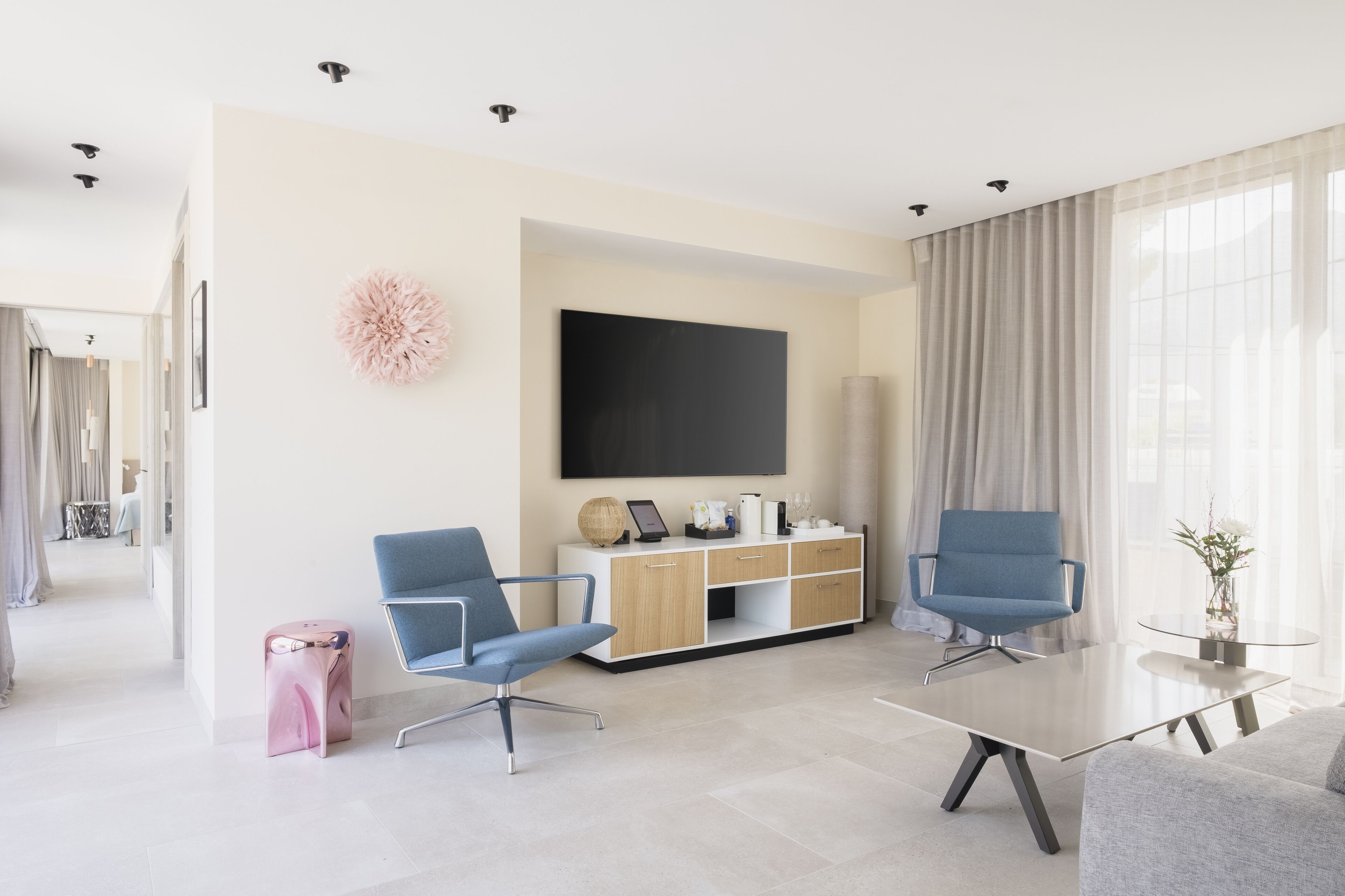 Una sala de estar moderna con dos sillones azules, una mesa de centro de vidrio, un televisor de pantalla plana y un mueble de madera.