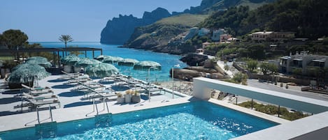 Una piscina techada, una piscina al aire libre, sombrillas
