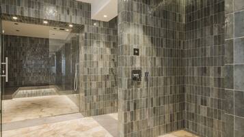Bathroom features a sleek design with a glass-enclosed shower and large tile flooring.