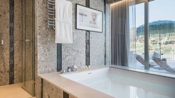 Un baño moderno con una bañera grande, una cabina de ducha de vidrio y vistas al exterior.