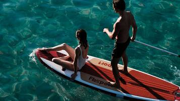 Eine Person steht auf einem Stand-Up-Paddleboard in klarem Wasser.