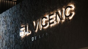 Fachada de piedra con letreros iluminados que dicen "EL VICENG DELANERO".