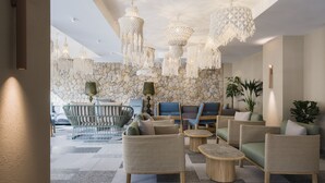 A modern lounge area with wicker furniture, a stone wall, and hanging chandeliers. - Hotel El Vicenç  de la Mar - Adults Only (+12) (Pollenca)