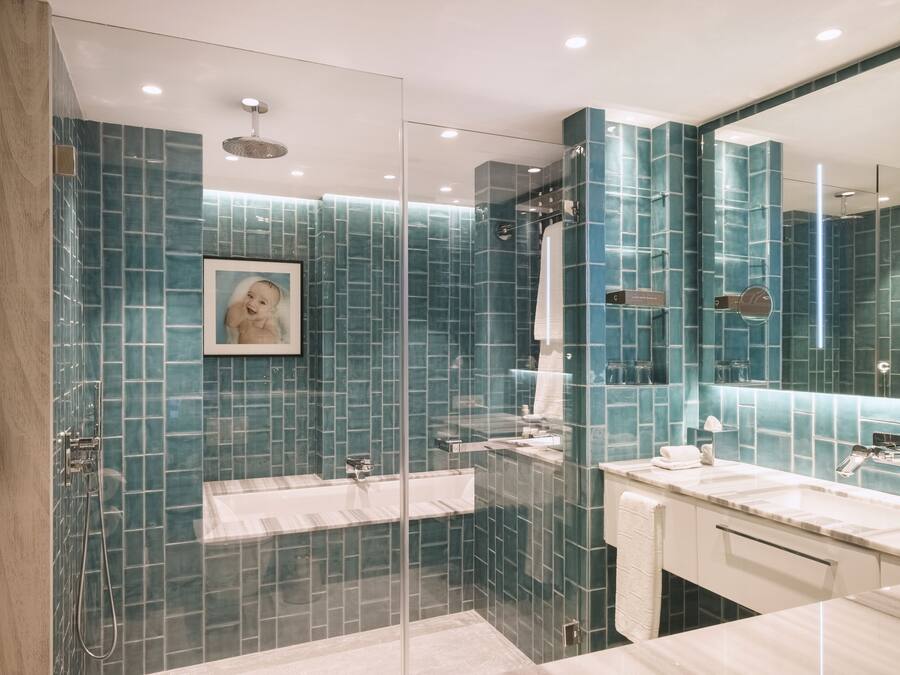 Uma casa de banho moderna com chuveiro envolto em vidro, um espelho grande e bancada de mármore.