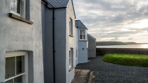 Une rangée de bâtiments blancs aux toits gris, un chemin de gravier et une zone herbeuse.