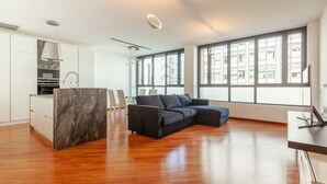 A modern apartment with a kitchen, a living area with a sofa, and large windows. - easyhomes - Madonnina view (Milan)