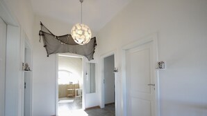 Un pasillo con puertas blancas, una lámpara colgante y una alfombra en el suelo.