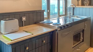 Eine kompakte Küche mit Einbauofen, Toaster und Fenster mit Blick auf einen Garten.