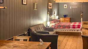 Ein Schlafzimmer mit einem Bett, einem Sessel, einem Holztisch und einer Kommode.