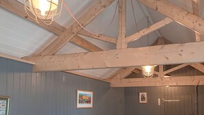 Ein Zimmer mit freiliegenden Holzbalken, einer weißen Decke und einer Pendelleuchte.