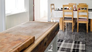 Un comedor con una mesa y sillas de madera, un tapete a cuadros y un mantel blanco.