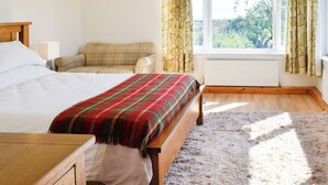 Un dormitorio con cama, sofá, ventana con cortinas y radiador.