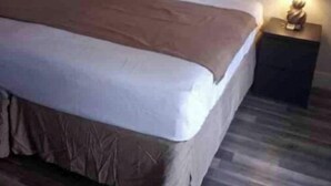 Tyypillinen hotellihuone, jossa on sänky, yöpöytä lampun kanssa ja puulattia.