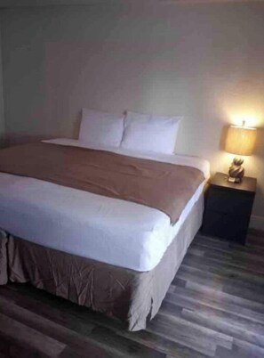 A standard hotel room with a bed, a nightstand with a lamp, and a wooden floor. - Private Suite # 11, five minutes walk to beach (Pompano Beach)