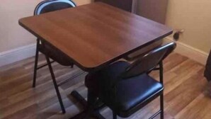Pieni ruokailutila, jossa on puinen pöytä ja kaksi mustaa tuolia.