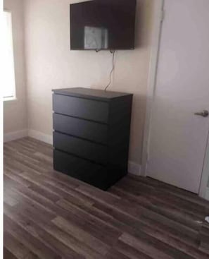 A room with a dark-colored dresser against a wall, a door to the right, and a window on the left. - Private Suite # 11, five minutes walk to beach (Pompano Beach)