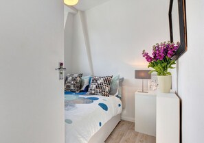 Relax in a serene bedroom with a large bed, nightstand, and mirror.