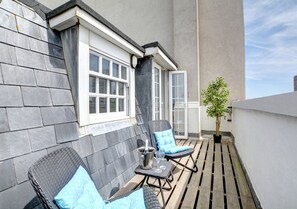 Relax on the balcony with two comfortable lounge chairs and a small table for a quiet moment.