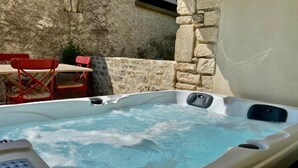 A hot tub with a control panel, set against a stone wall and red chairs. - LE PONT Junior Luxury Suite with private Jacuzzi (Martignargues)