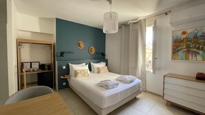 A hotel room with a bed, a desk, a chair, a wardrobe, and a painting on the wall. - LE PONT Junior Luxury Suite with private Jacuzzi (Martignargues)