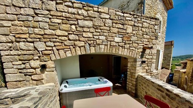 A stone wall with a stone oven, a table, and red chairs. - LE PONT Junior Luxury Suite with private Jacuzzi (Martignargues)