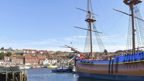 Un grand voilier était amarré dans un port, avec une ville en arrière-plan.