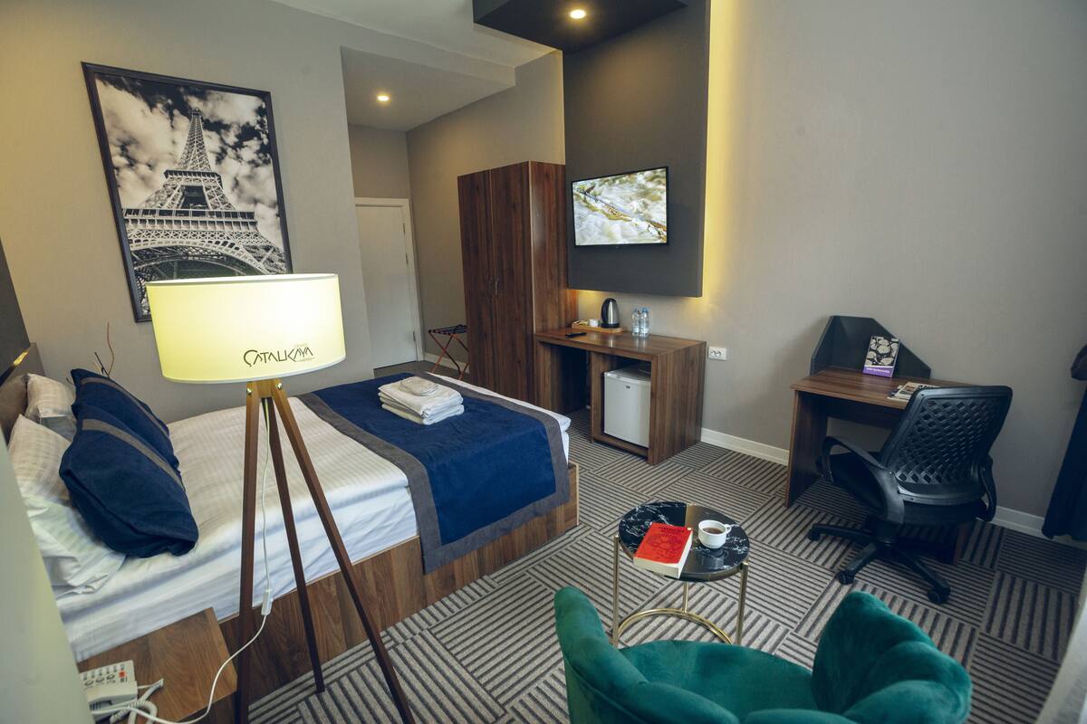 Une chambre d’hôtel avec un lit, un bureau, une chaise, une télévision et une lampe.