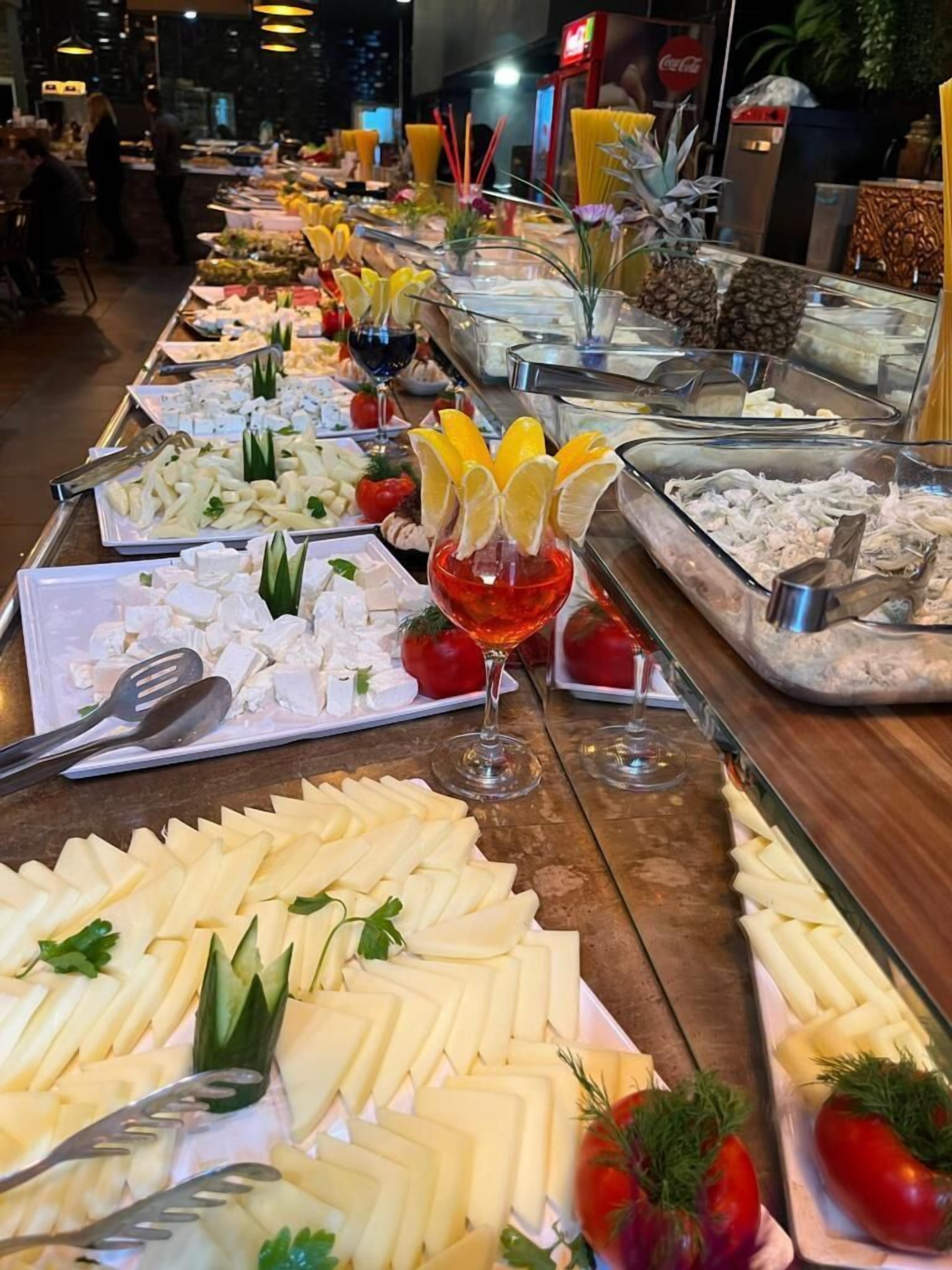 A buffet with various food items and a glass of red wine.