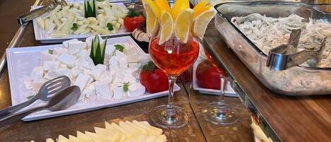A buffet with various food items and a glass of red wine.