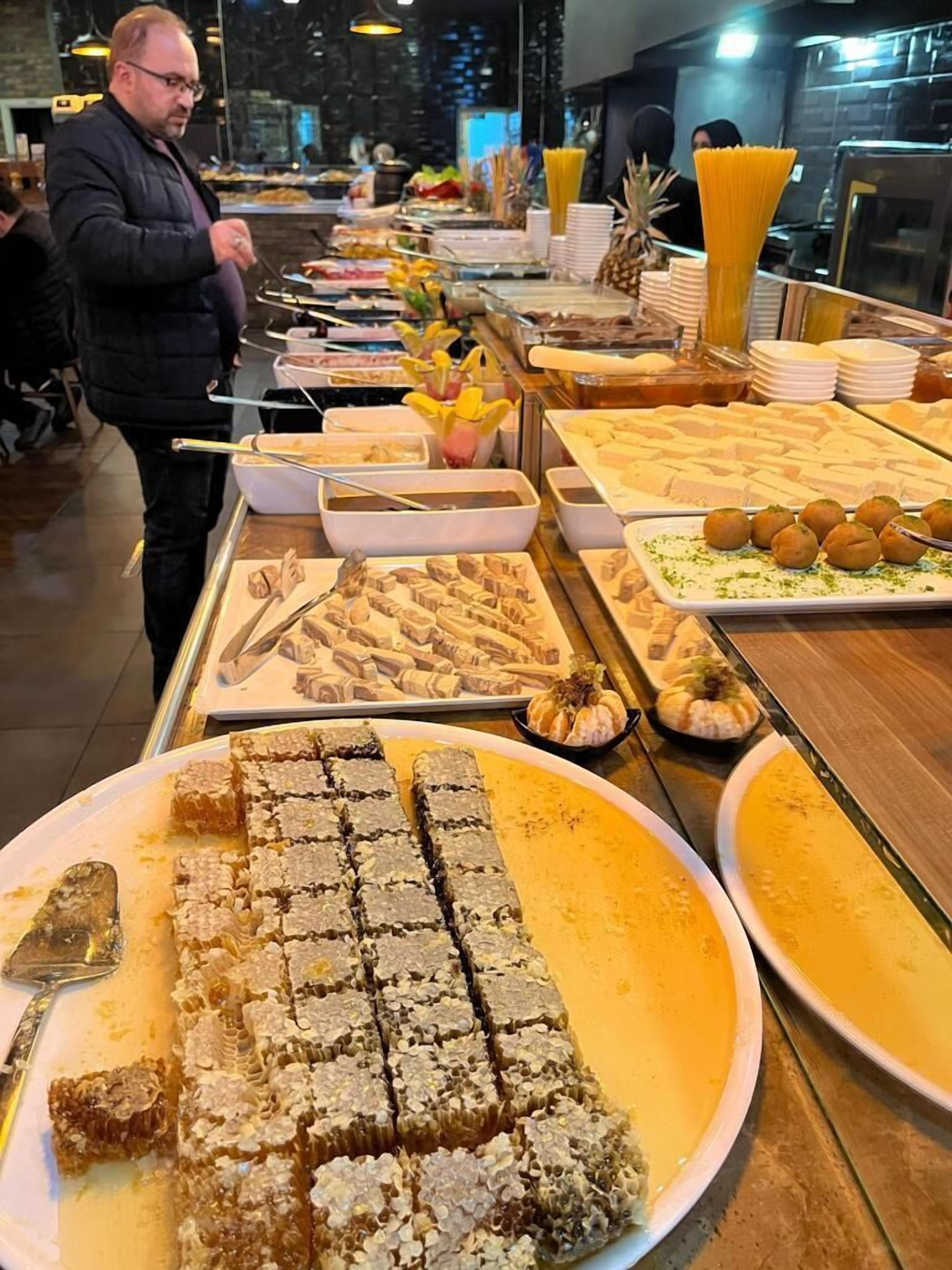 A buffet with various food items including honeycomb, pasta, and other dishes.