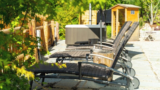 Ein Patio mit Sitzgelegenheiten im Freien, einem Whirlpool und einer Holzkonstruktion.