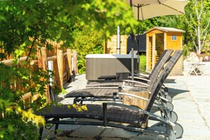 Un espace patio avec des sièges d’extérieur, un jacuzzi et une structure en bois.