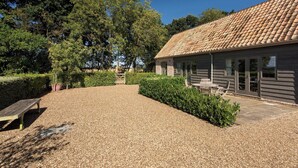 A building with a tiled roof, a gravel driveway, and a bench.
