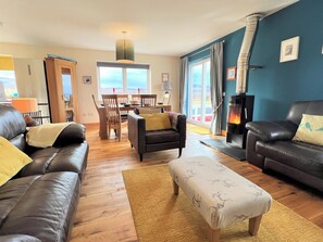 A cozy living room with leather sofas, a patterned ottoman, and a wood-burning stove. - 3 bedroom accommodation in Staffin, near Portree (Staffin, near Portree)