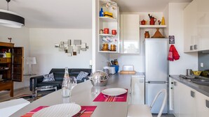 Una cucina moderna con mobili bianchi, un frigorifero bianco e un'area pranzo con un tavolo apparecchiato per due.