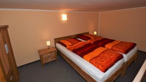 Une chambre avec deux lits, des têtes de lit en bois, une table de chevet avec une lampe et une armoire.